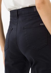 Donkerblauwe hoge taille broek met een gladde textuur, voorzien van twee achterzakken en subtiele stikdetails.