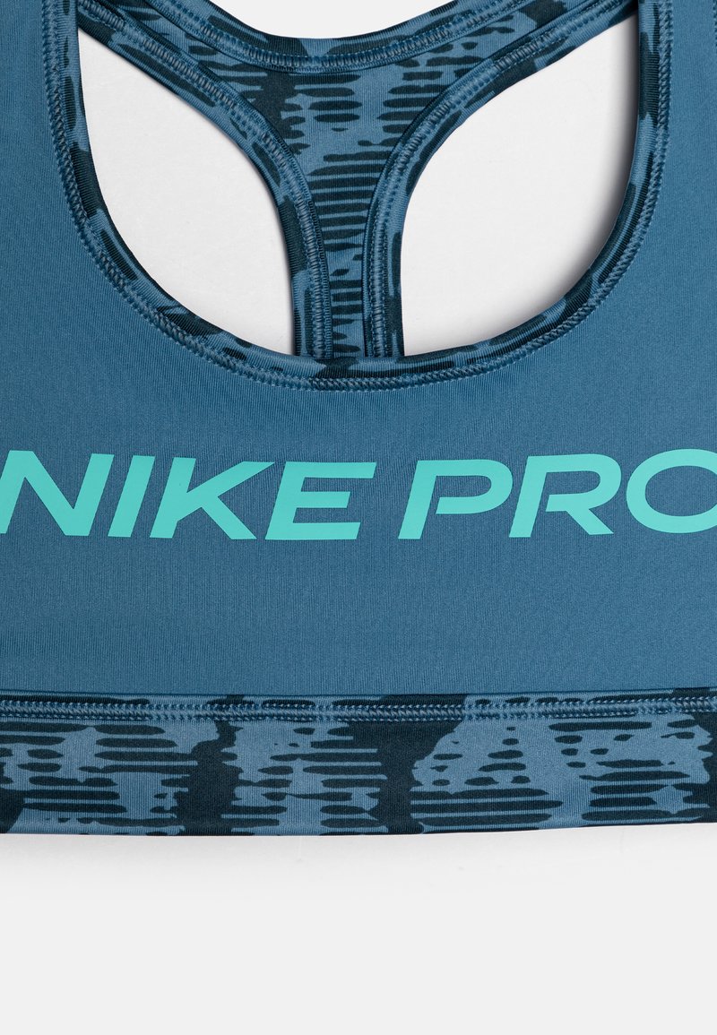 Blauer Sport-BH mit einem strukturierten Muster am unteren Rand, Nike Pro-Logo in Aqua und einem Racerback-Design für Flexibilität und Unterstützung.