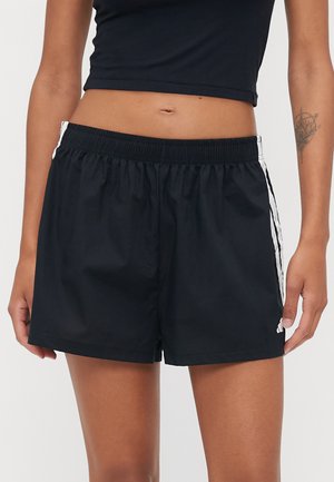 Shorts de sport noirs avec une taille élastique, des poches latérales et des rayures blanches sur les bords. Fabriqués en tissu lisse et léger.