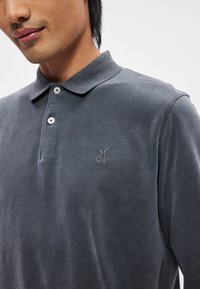 Γκρι πόλο μπλούζα με γιακά, που διαθέτει δύο κουμπιά, κεντημένο λογότυπο "MOP" και μαλακή υφή. Σχεδιασμένη με κλασική γραμμή.