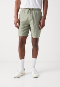 Lichtgroene short met koord in een textuurstof, met een relaxed fit. Gecombineerd met witte sneakers en sokken. Eenvoudig en functioneel design.
