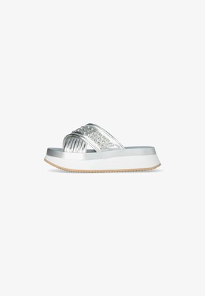 Sandali platform argento con tomaia lucida, caratterizzati da una fascia testurizzata decorata con strass piatti, e una suola in gomma bianca con una leggera aderenza.