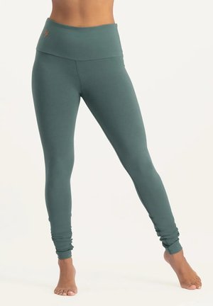 Türkise High-Waist-Leggings aus elastischem Stoff, mit glatter Textur und engem Schnitt, der sich an den Knöcheln verjüngt. Keine sichtbaren Logos.