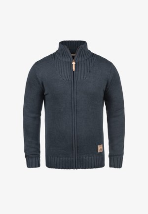 Marineblauwe gebreide cardigan met hoge kraag, volledige ritssluiting aan de voorkant, geribbelde manchetten en zoom, voorzien van een leren logopatch aan de onderzijde.