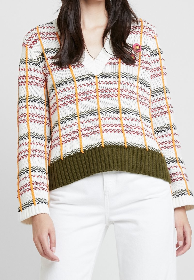 Suéter de punto con escote en V, que presenta una base blanca con franjas de patrones en rojo, naranja y negro. Dobladillo y puños acanalados en verde oliva.