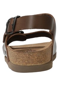 Sandale en cuir marron avec boucle ajustable, semelle en liège et semelle en caoutchouc plates dotées d'une finition texturée et d'un design à talon ouvert.