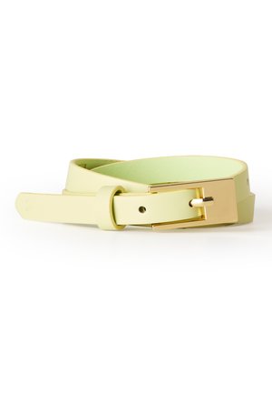 Ceinture en cuir jaune clair avec une boucle rectangulaire dorée, enroulée une fois et posée à plat sur une surface blanche.