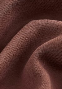 Tejido de punto en un cálido tono marrón, con una textura suave, costuras finas y apretadas, y sutilezas en las variaciones de grosor.