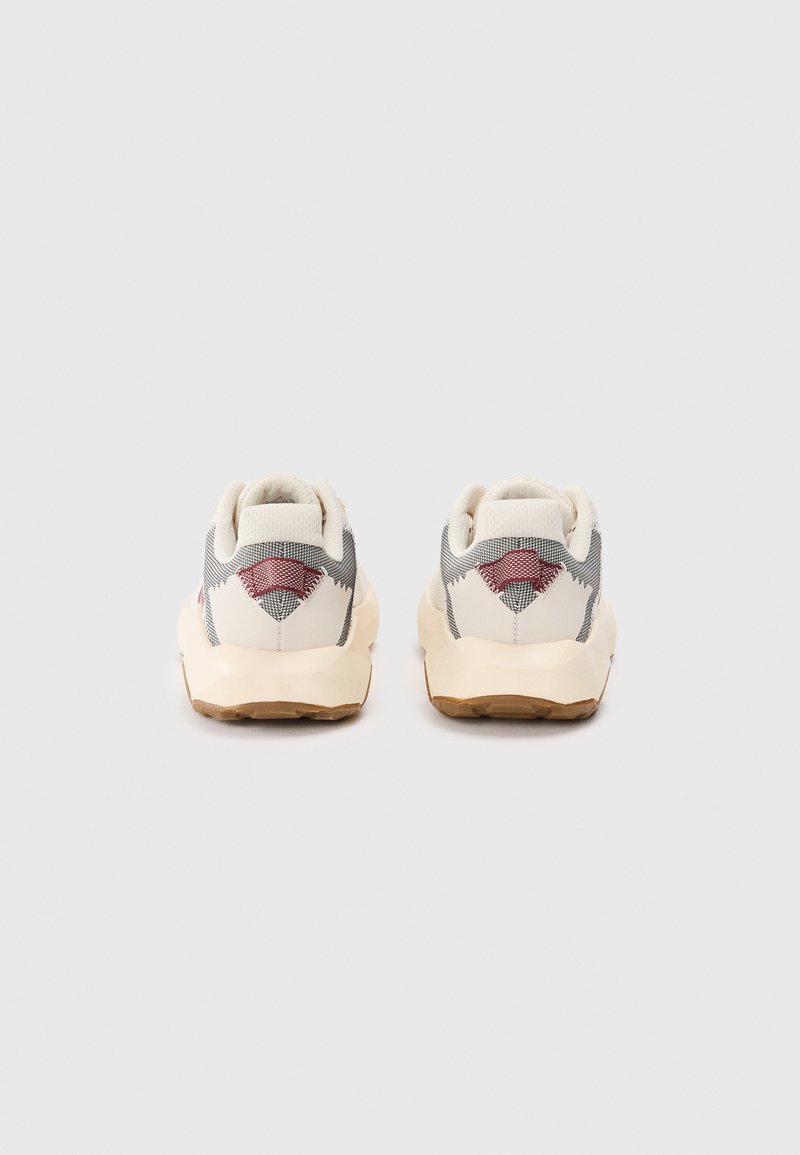 Herresneakers med en overdel i hvidt og gråt stof, tekstureret hæl og gummisål. Røde og grå detaljer på hælen tilføjer et pift.