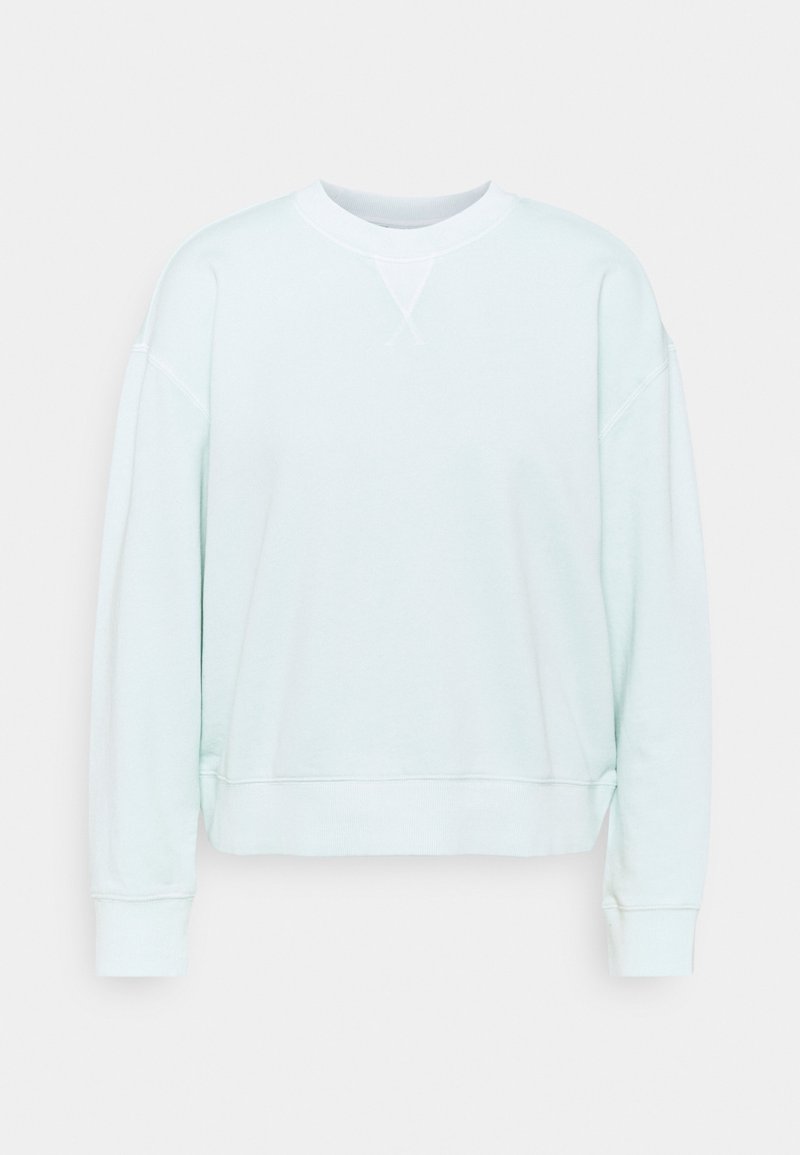 Jasnoniebieska bluza z miękkiego materiału. Posiada okrągły dekolt, długie rękawy oraz ściągacze na mankietach, o luźnym kroju i minimalnych detalach.