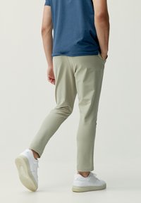 Ljusgröna, avsmalnande joggers med sidofickor, som är kombinerade med en kortärmad blå skjorta och vita sportskor. Slätt, elastiskt material.