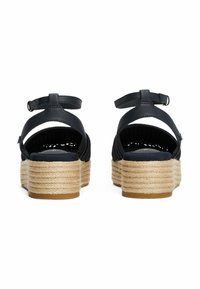 Sandalias de plataforma de cuero azul marino con tacones de cuerda trenzada, correas ajustables en el tobillo y parte trasera abierta. Material texturizado y construcción resistente.