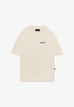 T-shirt en coton beige avec un col rond, au design surdimensionné, et un logo imprimé noir sur la poitrine gauche. Manches courtes à coupe droite.
