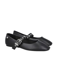 Zapatos planos negros hechos de material suave, con una correa en el tobillo y herrajes plateados, además de recortes circulares. Diseño de punta redondeada.
