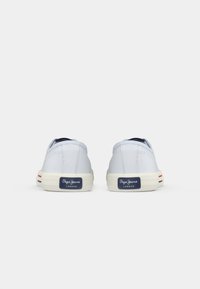 Canvas sneakers in light blue, featuring a textured surface, round toe, and a white rubber sole with navy and red striped accents.