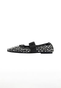 Zapato plano negro con punta afilada, adornado con tachuelas plateadas, presentando una correa de moño de satén en la parte superior. Textura suave y perfil bajo.