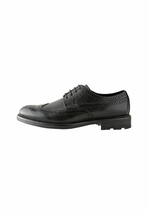 Zapato brogue de cuero negro con perforaciones decorativas, diseño de cordones, punta redonda y suela de goma texturizada para mayor adherencia.