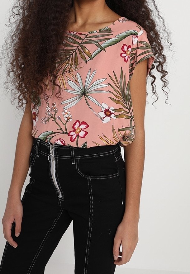 Blommig rosa blus med båtutskärning och korta ärmar, parat med högmidjade svarta jeans med vit sömnad och dragkedjedetalj.