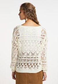 Háčkovaný svetr v off-white barvě, s otevřeným pletením, volným střihem a pružnými manžetami. Texturovaný vzor se zvlněnými detaily na lemu.