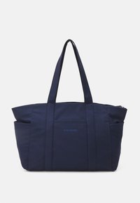 Marinblå tote-väska gjord av slitstark tyg, med topphandtag, dragkedjestängning och en ytterficka med en kontrasterande logodetalj.