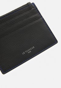 Porte-cartes en cuir noir avec surface texturée, plusieurs emplacements pour cartes et surpiqûre bleue contrastante. Logo affiché en argent.