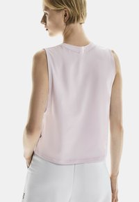 Mouwloos, lichtroze sporttop met een soepele textuur, ronde halslijn en subtiele stiksels, gecombineerd met lichtgrijze onderkleding.