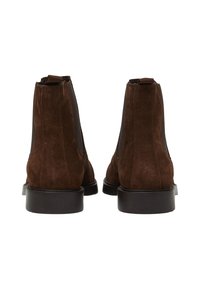 Bottines Chelsea en daim marron avec des panneaux latéraux élastiques, des semelles en caoutchouc durables et une finition lisse, dotées d'une languette à l'arrière.
