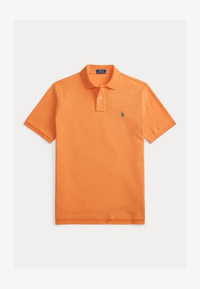 Polo orange en coton, avec un col classique, une patte de boutonnage à deux boutons, des manches courtes, et un petit logo vert sur la poitrine.