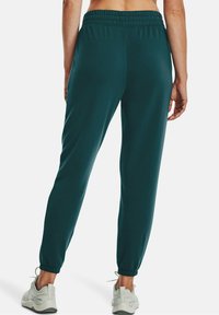 Türkise Jogginghosen aus weichem Material mit einem gerafften Bund, elastischen Bündchen und seitlichen Taschen. Kombiniert mit leichten Turnschuhen.