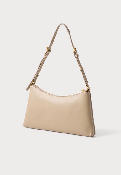 Sac à main en cuir beige avec bandoulière réglable et accessoires dorés, présenté sur un fond uni clair.