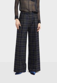 Kalhoty s širokým střihem v námořnickém kostkovaném vzoru; obsahují světle zelené a bílé překrývající se linie; měkká textura a precizní střih.