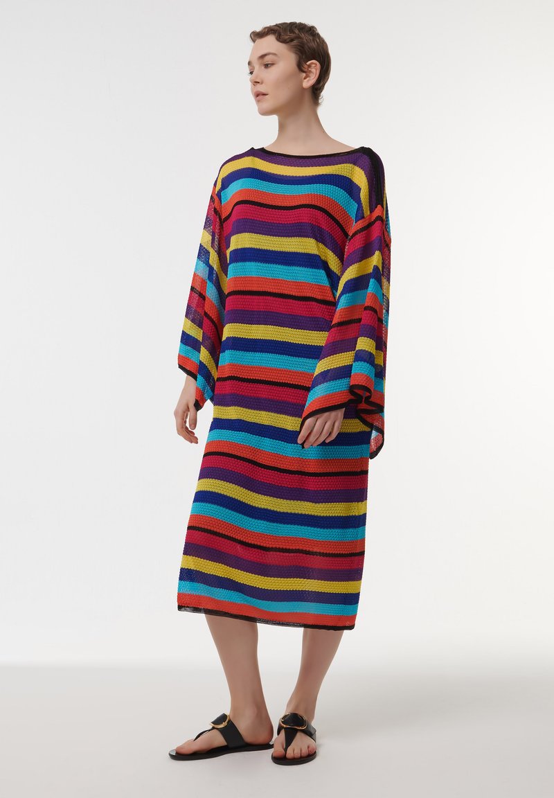 Vestido de punto a rayas multicolor con mangas amplias, corte holgado y largo hasta la rodilla. Las rayas incluyen rojo, azul, amarillo y púrpura.