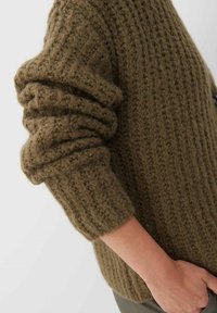 Olivgrön stickad tröja med ribbat mönster och nedvikta ärmslut, med en avslappnad passform och tjockt garn för värme.