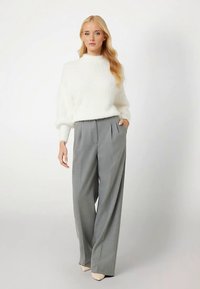 Hvid, luftig sweater med høj hals, kombineret med lysegrå, plisserede vidde bukser med løs pasform og glat tekstur.