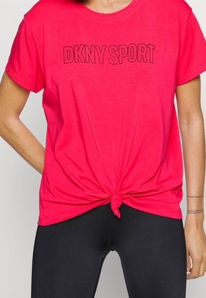 Person wearing bright pink DKNY SPORT t-shirt tied in a front knot, paired with black leggings, visible from neck to mid-thigh.