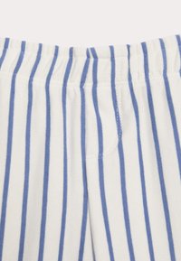 Tessuto bianco con righe verticali blu; vita elastica con texture arricciata; materiale morbido e leggero; nessun hardware o accenti visibili.