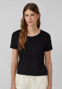 T-shirt noir à manches courtes en jersey doux, présentant un col rond et des ourlets roulés, avec une coupe décontractée.