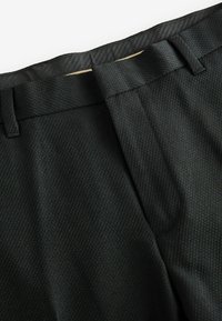 Schwarze, strukturierte Hosen mit einem dezenten diagonalen Muster, ausgestattet mit einem glatten Taillenbund, Gürtelschlaufen und einer polierten Optik.