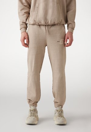 Beige joggingbroek met een elastische tailleband en boorden, voorzien van een subtiel logo op het bovenbeen en een zachte, gestructureerde stof.
