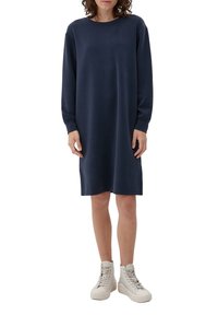 Mörkblå långärmad klänning i mjukt tyg, med en avslappnad passform och rund halsringning, i kombination med vita högskurna sneakers.