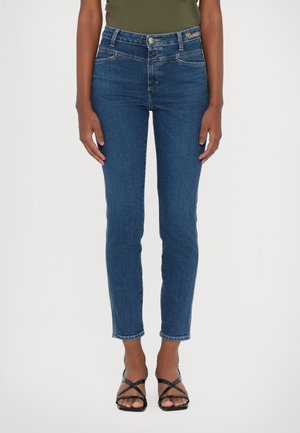 High-waisted dark blue jeans with a slim fit, featuring front pockets and a subtle stitch detail, paired with black strappy sandals.