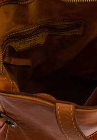 Braune Lederhandtasche mit einem Reißverschlusstasche, Stofffutter und einem Etikett mit der Aufschrift "VENEZIA MADE IN ITALY", das über Steppdetails verfügt.