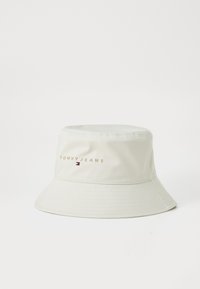 Bucket hat in cream color made of smooth fabric. Features "TOMMY JEANS" embroidered on the front with a small logo accent.