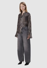 Leopardprint, button-up shirt met lange mouwen; gecombineerd met ontspannen grijze spijkerbroek; en puntige zwarte hakken.
