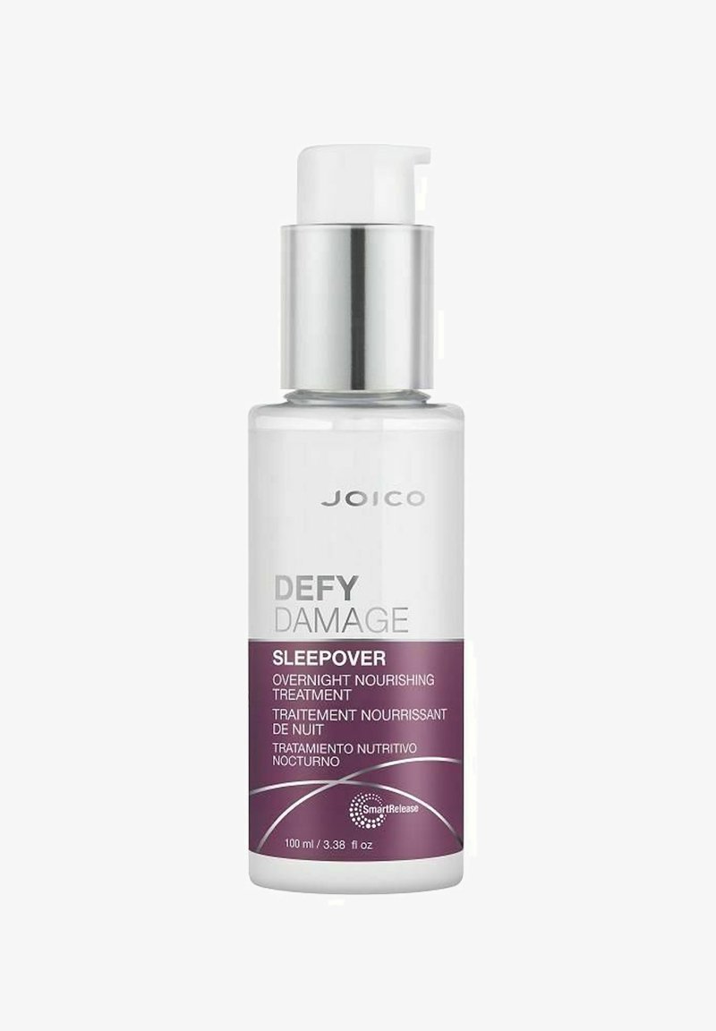 Transparent glasflaska med en vit pumpkork och silverdetaljer. Har lila och vita etiketter med produktnamn och information. 100 ml kapacitet.