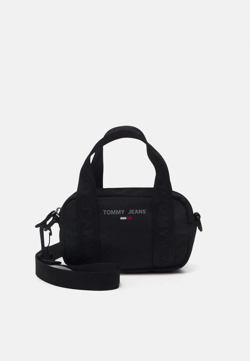 Petit sac à main noir Tommy Jeans avec deux petites poignées, une bandoulière amovible et un logo avec le drapeau rouge, blanc et bleu à l'avant.