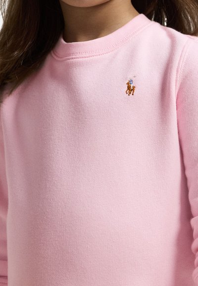 Hele roosa puuvillane dressipluus, millel on vasakul rinnal väike pruun ja sinine tikand hobuse logo, ümar kaelus.