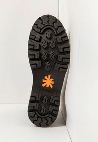 Semelle de chaussure en caoutchouc noir avec des motifs de semelle profonds, arborant un logo en forme d'étoile orange vif et une surface texturée pour une meilleure adhérence.