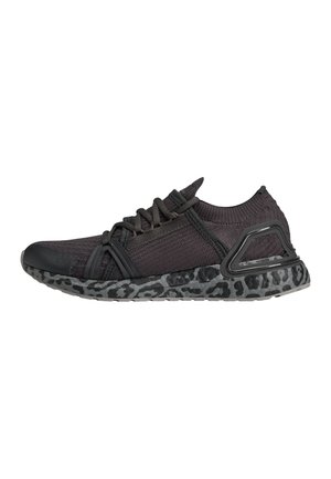 Czarny dziany sportowy sneaker z zapięciem na sznurowadła, amortyzowaną podeszwą z szarym wzorem w panterkę i czarną ramą wspierającą piętę.
