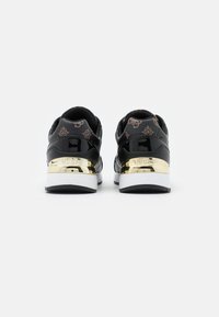 Sneakers neri con una finitura lucida, dettaglio dorato sul tallone e tessuto decorato al collo. Presentano una suola intermedia bianca e una suola esterna nera.